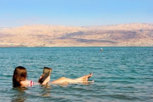 young woman reads a book floating in the Dead Sea in Israel